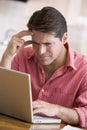 Man in kitchen using laptop frowning Royalty Free Stock Photo