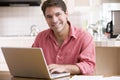 Man in kitchen using laptop smiling Royalty Free Stock Photo