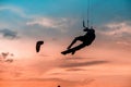 Man kitesurfer athlete jumping at sunset, silhouette at dusk man doing board greab Royalty Free Stock Photo