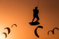 Man kitesurfing jump, kite surfer jumping at sunset on orange background between kites in the ai, kiteboarding at sunset, kitesurf Royalty Free Stock Photo