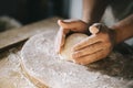 Man kneading and baking homemade pizza dough in the kitchen. Closeup on baker`s hands preparing loaf of bread Royalty Free Stock Photo