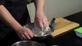 Man kneading dough with his hands in a metal bowl at the kitchen. Art. A cook preparing dough, mixing ingredients with Royalty Free Stock Photo