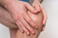 Man with knee pain is holding his aching leg