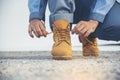 Man kneel down and tie shoes industry boots for worker. Close up shot of man hands tied shoestring for his construction brown Royalty Free Stock Photo