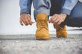 Man kneel down and tie shoes industry boots for worker. Close up shot of man hands tied shoestring for his construction brown