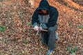 The man is kneeling in prayer and holding a bloody wooden cross in his hand