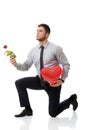 Man kneeling with red rose and heart balloon.