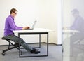 Office worker sitting on kneeling stool,correct sitting position Royalty Free Stock Photo