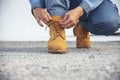 Man kneels down rope tie shoes industry boots for worker. Close up shot of man hands tied shoestring for his brown construction Royalty Free Stock Photo