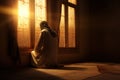 the man kneels in quiet and praying by the window