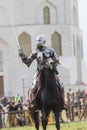 A man knight riding a horse on the battlefield - people watching behind the fence