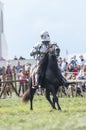 A man knight with a sword riding a horse on the battlefield - people watching behind the fence Royalty Free Stock Photo