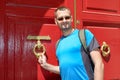 A man knocking on a red door with a knocker