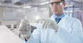 Man in lab coat with glass device and white graph with flare against blurry lab Royalty Free Stock Photo