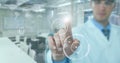 Man in lab coat pointing at white interface with flare against blurry lab with teal overlay Royalty Free Stock Photo