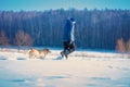 A man with a labrador retriever dog walking across a snowy field