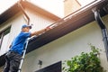 Man on ladder cleaning house gutter Royalty Free Stock Photo