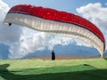 A man landed with a red and white paraglider on a background of blue sky and clouds