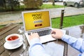 Man with laptop activating promo code at wooden table outdoors, closeup