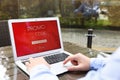 Man with laptop activating promo code at wooden table outdoors, closeup