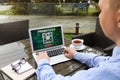 Man with laptop activating promo code at wooden table outdoors, closeup