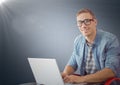 Man with laptop against navy background with flare Royalty Free Stock Photo