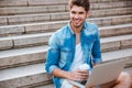 Man with laptop drinking take away coffee on the staircase Royalty Free Stock Photo