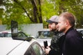 Man with a laptop in parking lot in yard near car is doing manipulations with cyber system, concept. Royalty Free Stock Photo