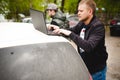 Man with a laptop in parking lot in yard near car is doing manipulations with cyber system Royalty Free Stock Photo