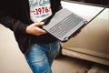 Man with a laptop in parking lot in yard near car is doing manipulations with cyber system Royalty Free Stock Photo