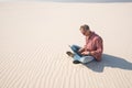 Man with a laptop sits alone in the middle of the desert Royalty Free Stock Photo