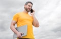 man with laptop speaking on smartphone on sky background. modern life Royalty Free Stock Photo
