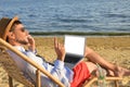 Man with laptop talking by mobile phone on beach. Business trip Royalty Free Stock Photo