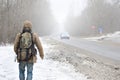 A man with a large backpack walks along a suburban asphalt road Royalty Free Stock Photo