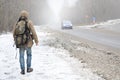 A man with a large backpack walks along a suburban asphalt road Royalty Free Stock Photo