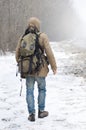 A man with a large backpack walks along a suburban asphalt road Royalty Free Stock Photo