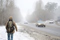 A man with a large backpack walks along a suburban asphalt road Royalty Free Stock Photo