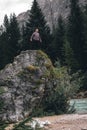 Man on a large stone, a boulder, among the incredibly beautiful river of turquoise color, vertical photo. Dolomites mountains,