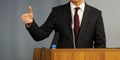 A man - a lawyer, politician, businessman or official speaks from the rostrum. Gesture and microphone