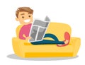 Man laying on the couch and reading a newspaper.