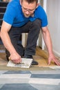 Man laying floor tiles with tiling trowel
