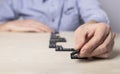 Man laying out dominoes on table. Strategy, business plan drawing up, paving way, planning concept. Hands closeup. Path Royalty Free Stock Photo