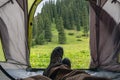 Man is laying in tent in beautiful mountains. Camping in mountains. Tourism hiking concept.