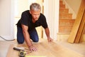 Man laying wood panel flooring during a house refurbishment