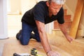 Man laying wood panel flooring during a house refurbishment Royalty Free Stock Photo