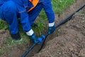 A man lays in the excavated trench, a water pipeline and an electric cable