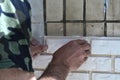 A man lays light tiles on an old balcony wall