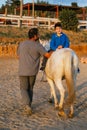 Man leading a child with disabilities on a horse at an equestrian center. Royalty Free Stock Photo