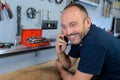 man leaning on bench in workshop and talking on telephone Royalty Free Stock Photo