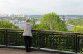 A man leaning on the railing of the fence, admiring the view of Kiev on Vladimirskaya Gorka